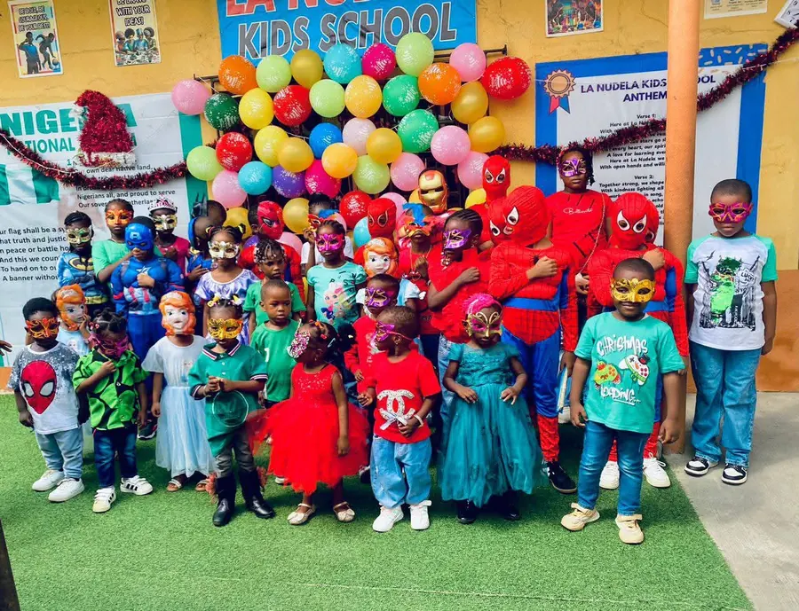 Pupils in costumes and masks in front of a balloon display on Costume Day