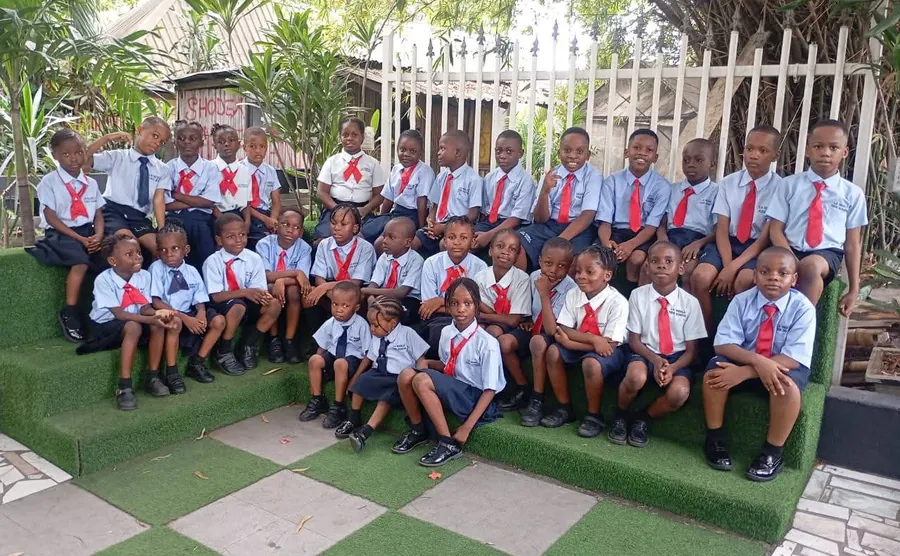 Pupils of La Nudela Innovative School in school uniform, seated together in the school grounds